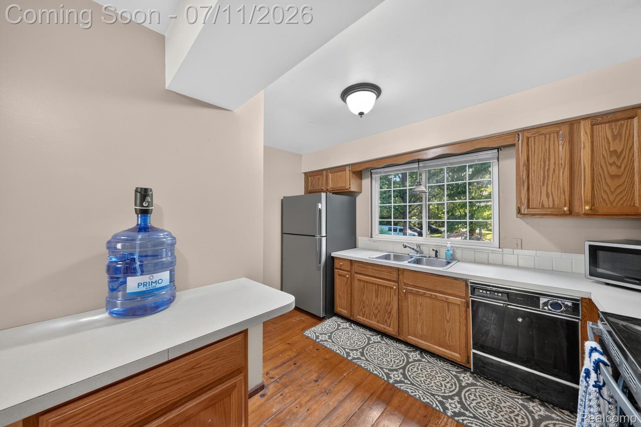 4430 North Center Road Flint, MI 48506 - Photo 10 of 49 Kitchen featuring wood-finish flooring, oak cabinetry, white countertops, and a white tile backsplash