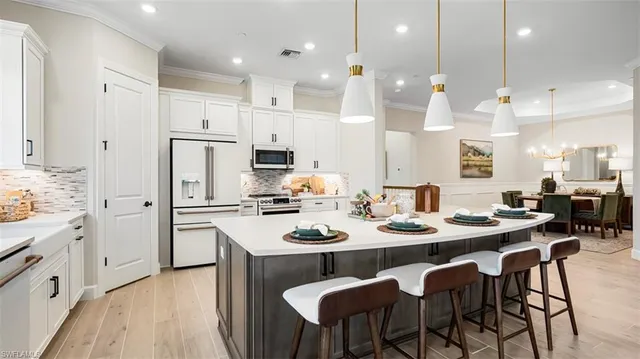 a kitchen with stainless steel appliances kitchen island granite countertop a dining table chairs and white cabinets