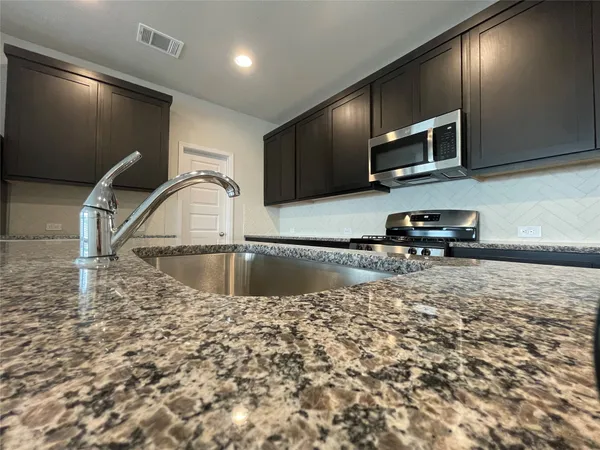 a kitchen with stainless steel appliances granite countertop a sink a stove and a refrigerator