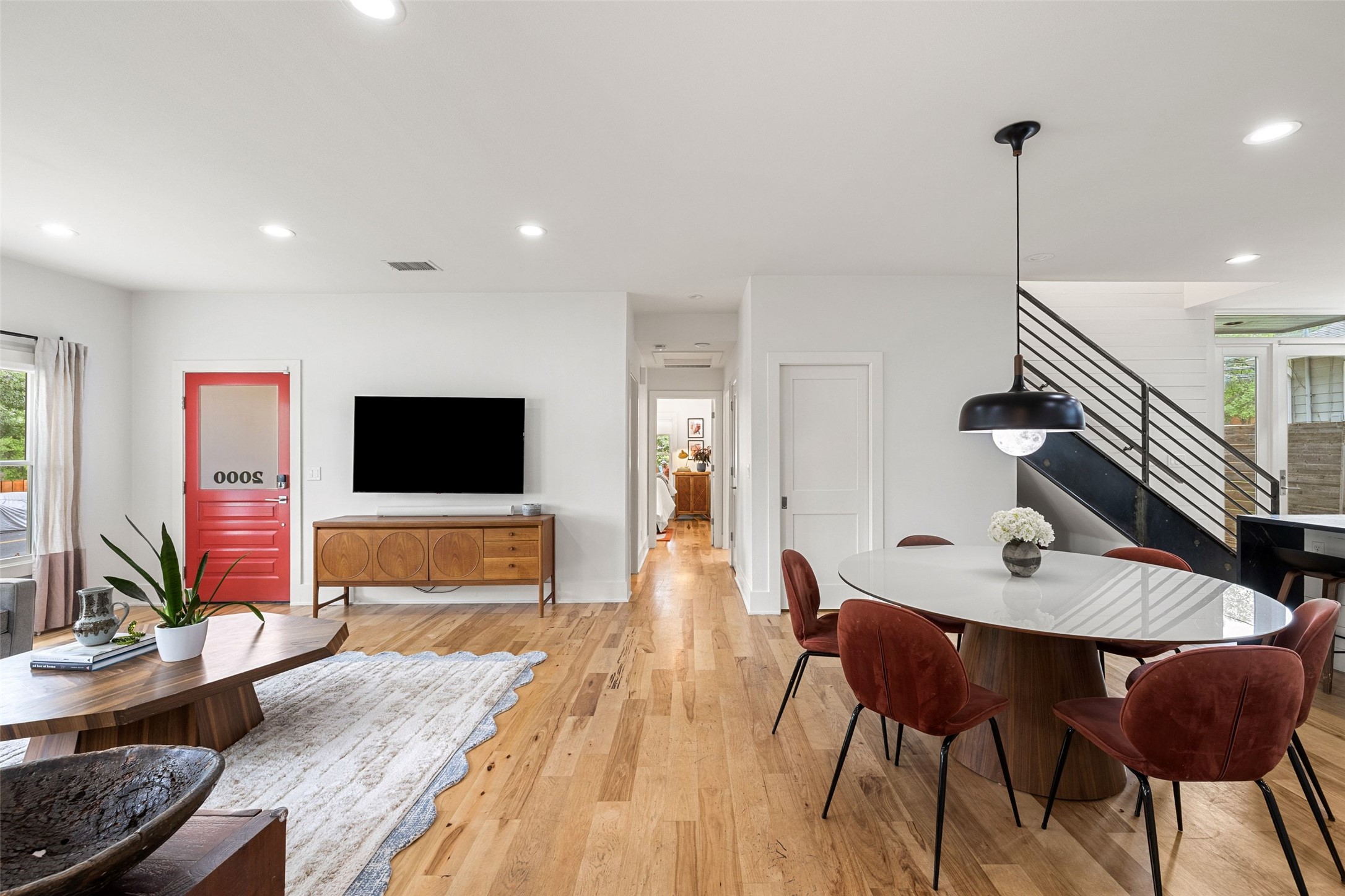 2000 Rundell Place Austin, TX 78704 - Photo 12 of 38 Blonde hardwood floors flow through an open concept living and dining space with a contemporary hanging light fixture.