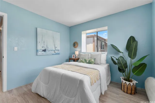 a bedroom with a large bed wooden floor and potted plant
