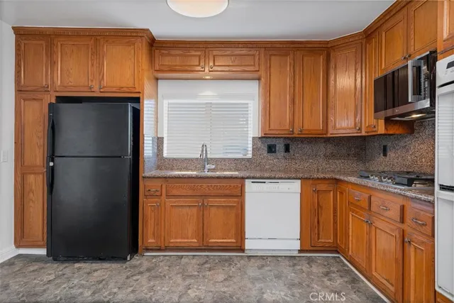 a kitchen with granite countertop wooden cabinets and a refrigerator
