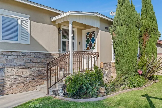 a view of a house with a small yard plants and large tree