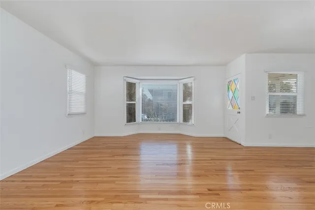 a view of an empty room with window and wooden floor