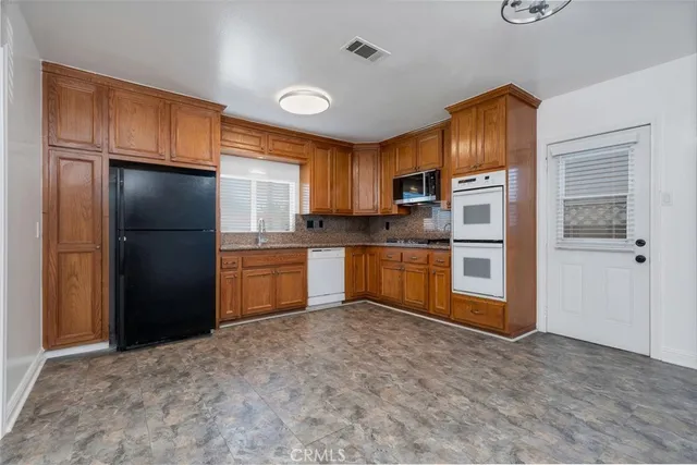 a kitchen with granite countertop a refrigerator and cabinets