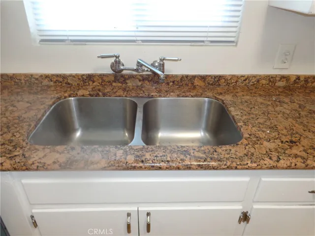 a kitchen with granite countertop cabinets stainless steel appliances a sink and a window