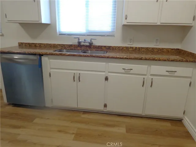 a kitchen with a sink cabinets wooden floor and a window