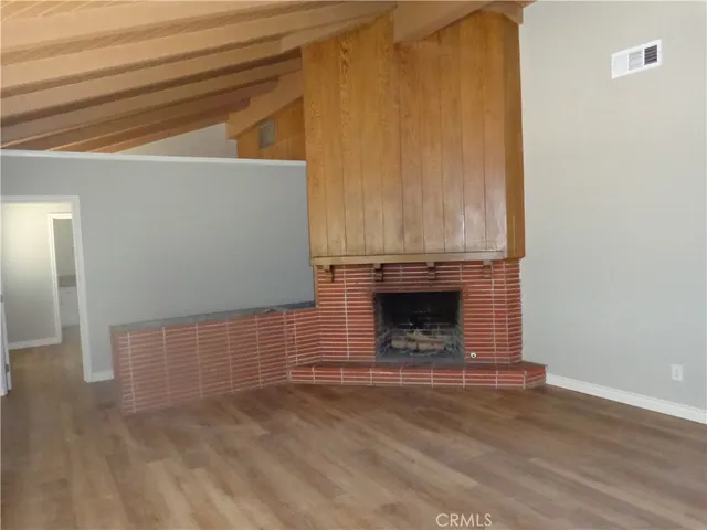 a view of empty room with wooden floor and fireplace