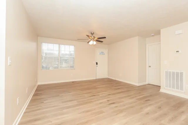 a view of an empty room with wooden floor and a window