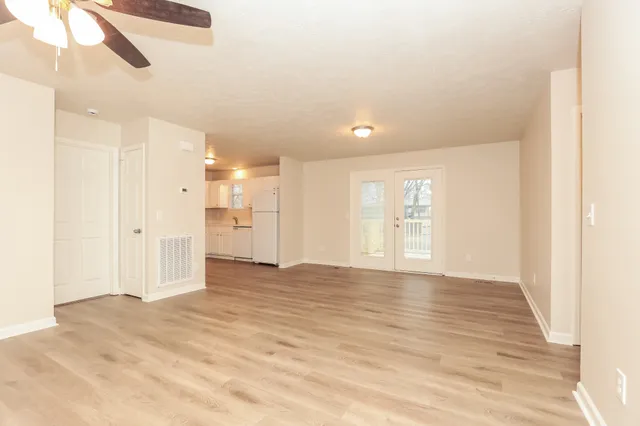 a view of an empty room with wooden floor and windows
