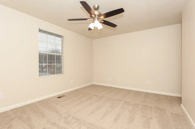 an empty room with a window and a ceiling fan