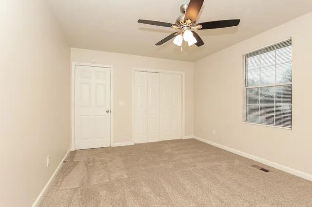 an empty room with a window and a fan