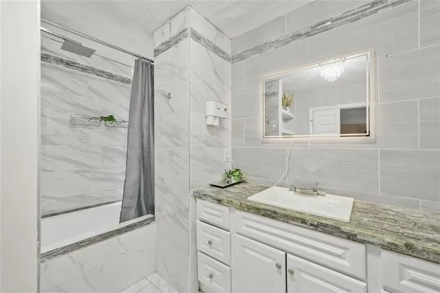 a bathroom with a granite countertop sink a mirror and a shower