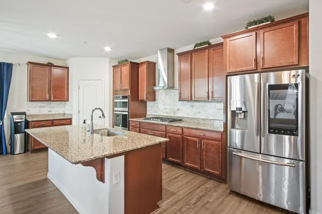 a kitchen with stainless steel appliances granite countertop a refrigerator a sink and a stove