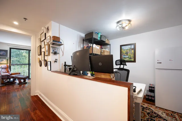 a view of a hallway with wooden floor and workspace