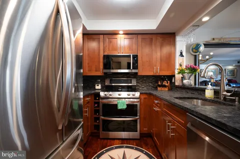 a kitchen with stainless steel appliances granite countertop a refrigerator a stove and a sink