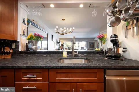a kitchen with granite countertop a sink a stove and a wooden cabinets