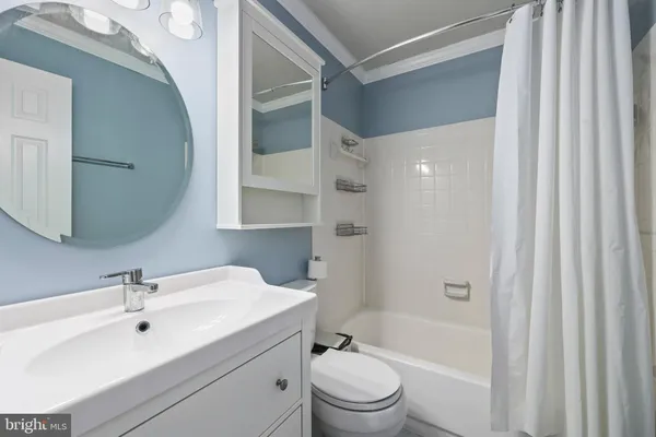 a bathroom with a bathtub shower sink vanity mirror and toilet