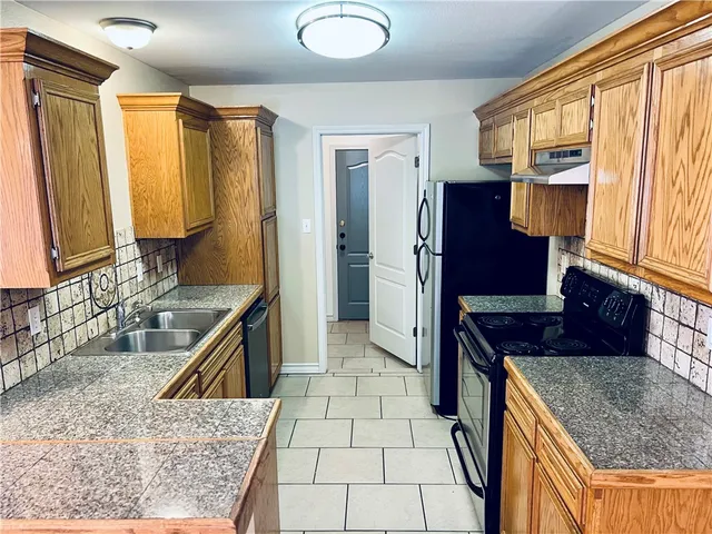 a kitchen with stainless steel appliances granite countertop a refrigerator a stove and a sink