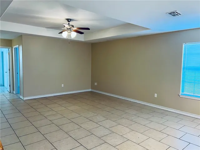 a view of an empty room and chandelier fan