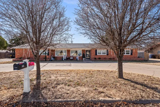 a front view of a house with a yard covered with snow and trees