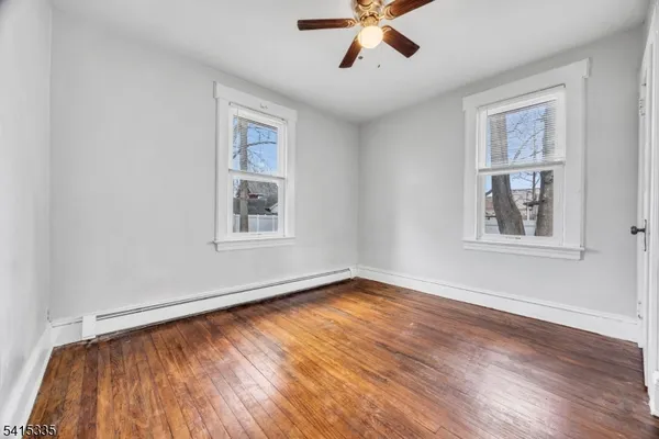 a view of empty room with wooden floor and fan