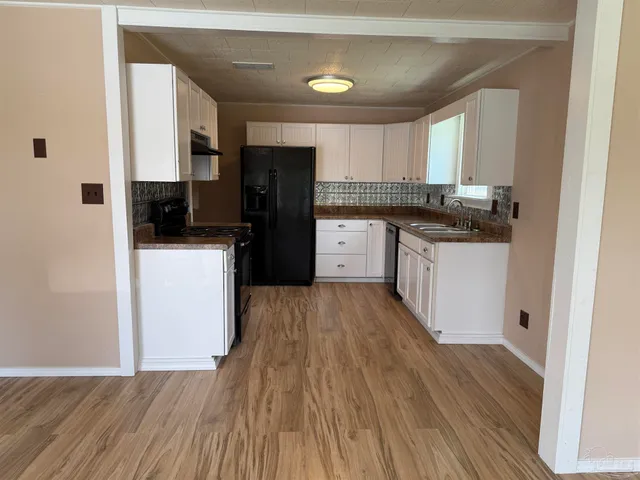 a kitchen with stainless steel appliances a refrigerator sink and wooden floor