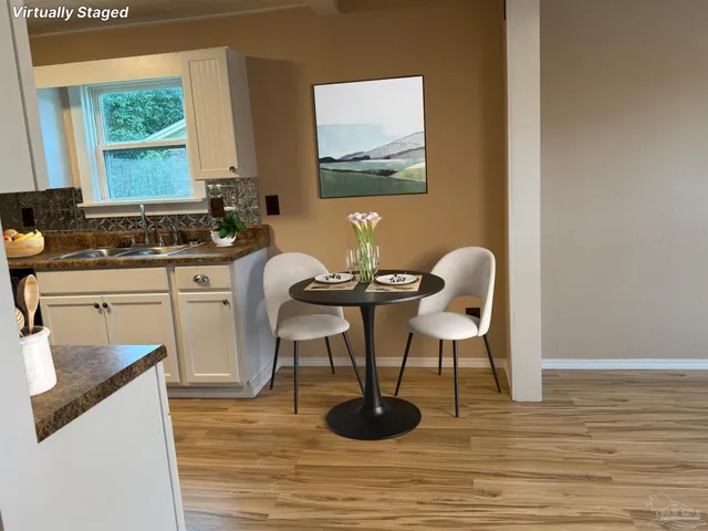 a view of a kitchen and dining room with furniture wooden floor a rug and a window