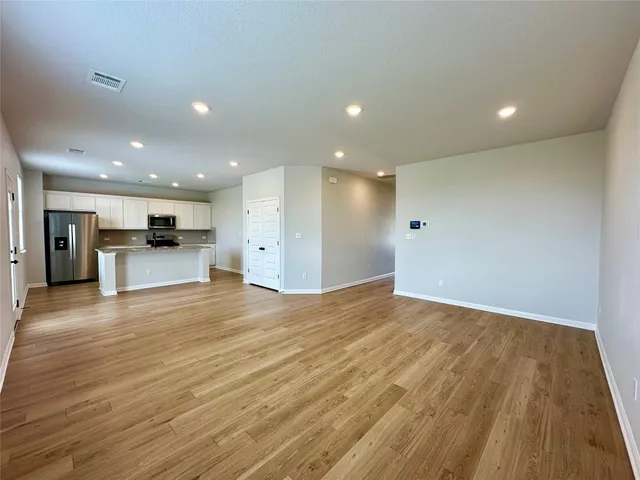 a view of kitchen with kitchen island granite countertop refrigerator and stove top oven