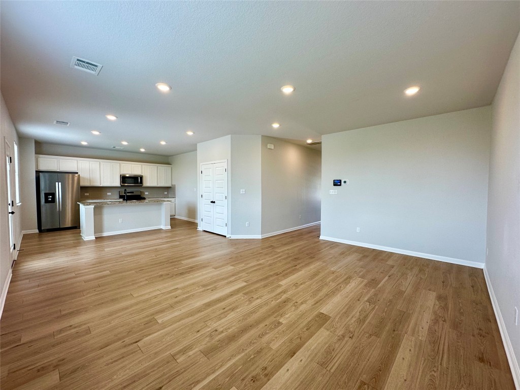 a view of kitchen with kitchen island granite countertop refrigerator and stove top oven