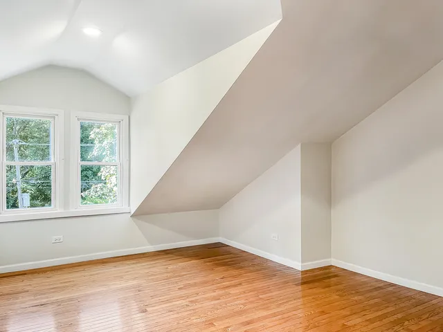 a view of an empty room with wooden floor and windows
