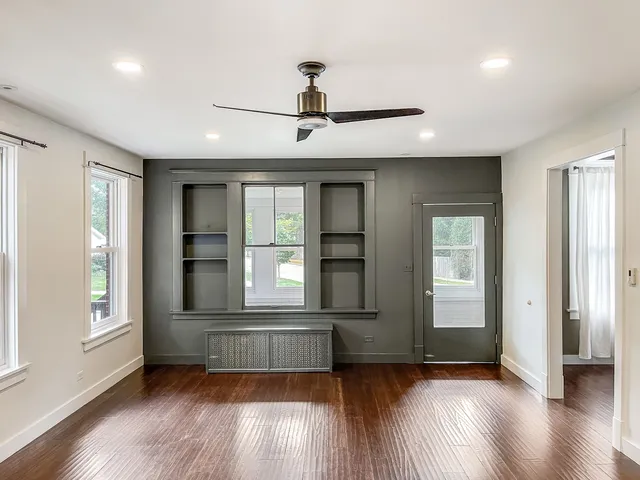 a view of an empty room with wooden floor and a window