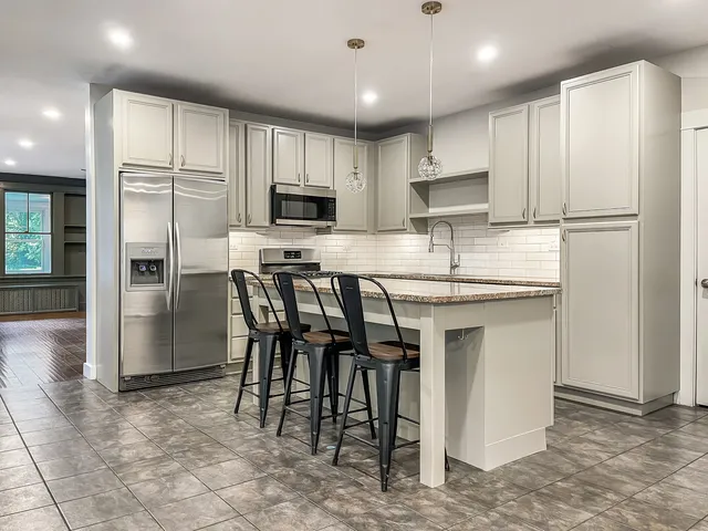 a kitchen with kitchen island a refrigerator stove microwave and cabinets