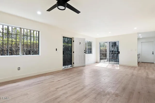 a view of an empty room with a window and wooden floor