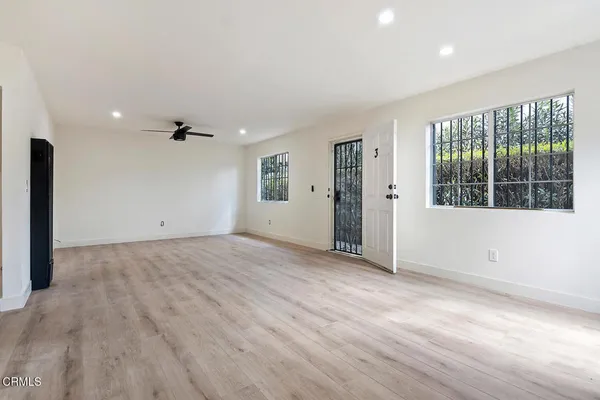 an empty room with wooden floor and windows