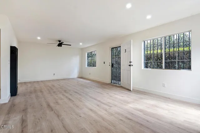 an empty room with wooden floor and windows