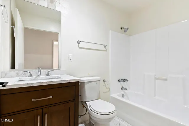 a bathroom with a granite countertop sink toilet a large mirror a bathtub and shower