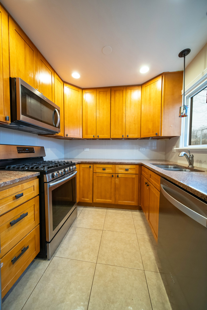 1504 Chippewa Trail Wheeling, IL 60090 - Photo 9 of 28 a large kitchen with stainless steel appliances granite countertop a stove a sink and a microwave