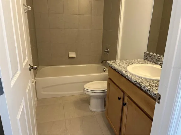 a bathroom with a granite countertop toilet a sink and a bathtub