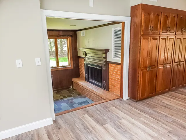 a view of an empty room with wooden floor fireplace and a window