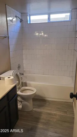 an empty room with wooden floor and a kitchen