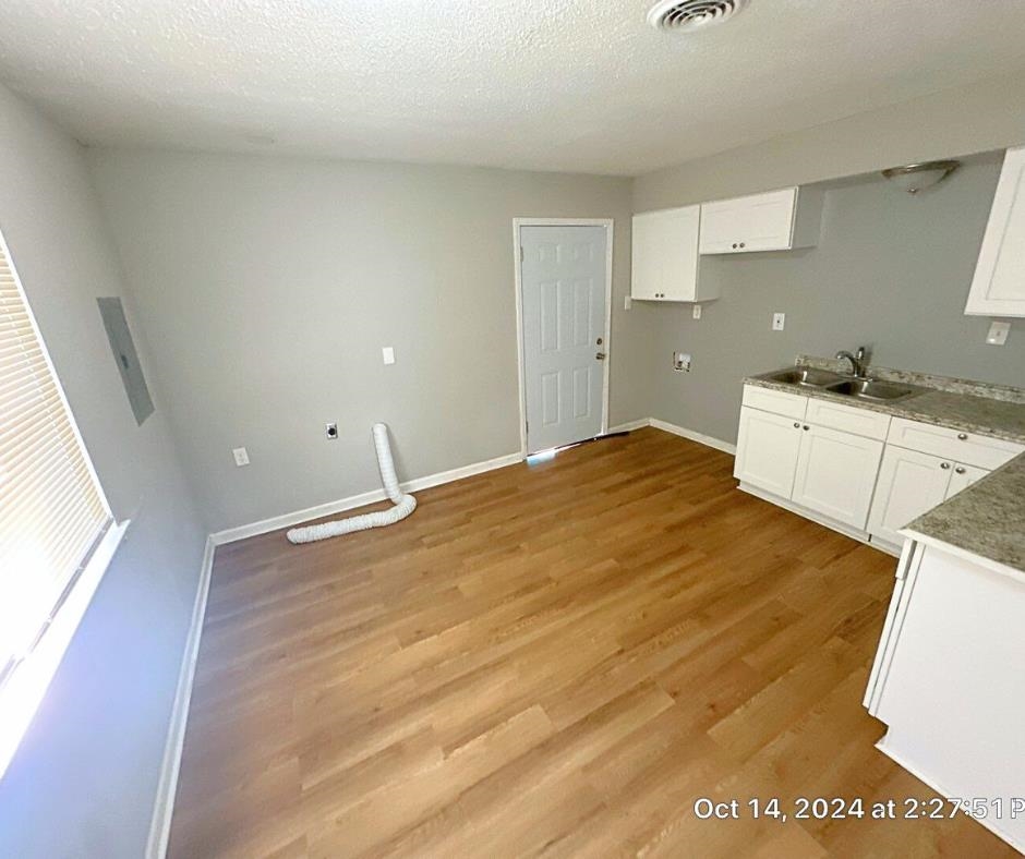 3747 Parakeet Road Memphis, TN 38109 - Photo 7 of 9 Kitchen with a textured ceiling, light hardwood / wood-style flooring, white cabinetry, and sink