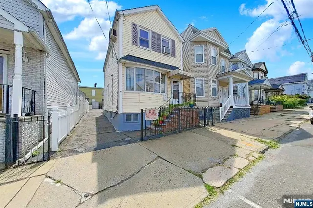 a view of a house with a barbeque and wooden stairs