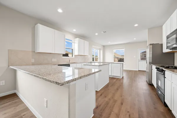 a large kitchen with stainless steel appliances granite countertop a lot of counter space and wooden floor