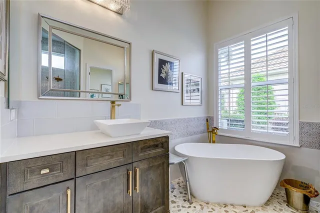 a bathroom with a tub a sink and mirror