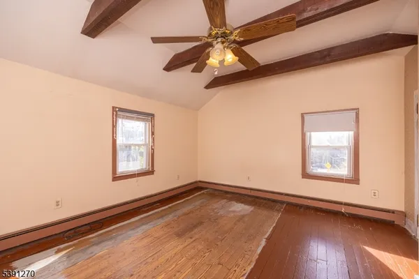 an empty room with wooden floor fan and windows