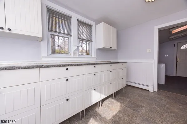 a kitchen with white cabinets and a window