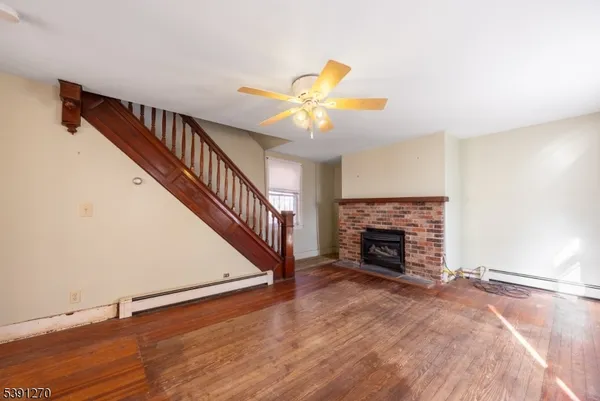 a view of a livingroom with a fireplace a ceiling fan and a fireplace