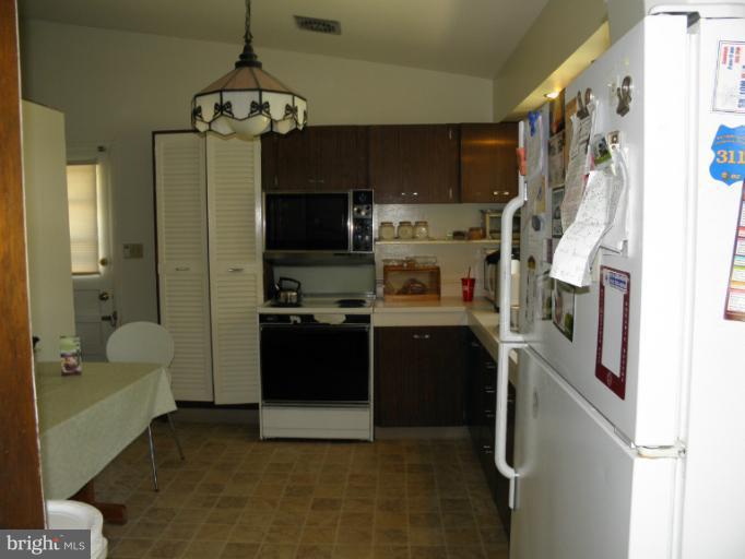 2323 Micarol Road Baltimore, MD 21209 - Photo 5 of 6 a kitchen with stainless steel appliances granite countertop a refrigerator a sink dishwasher a stove and a dining table with wooden floor