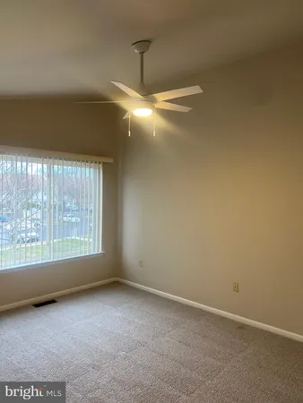 an empty room with windows and fan